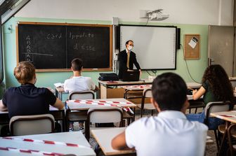 Insegnante a scuola con mascherine e distanziamento