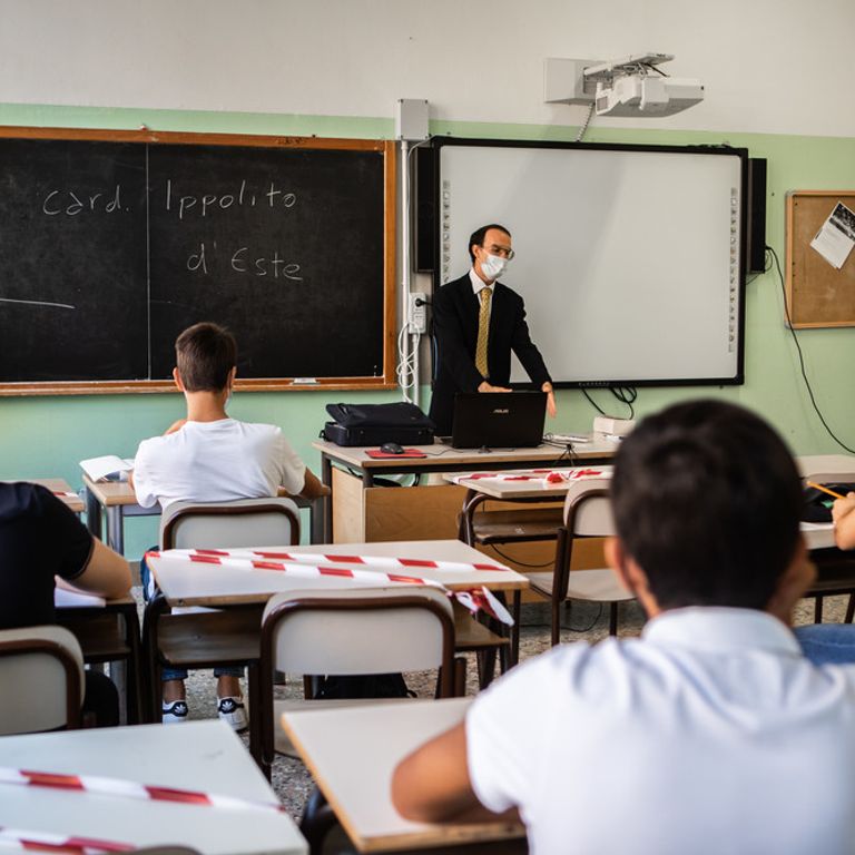 Insegnante a scuola con mascherine e distanziamento