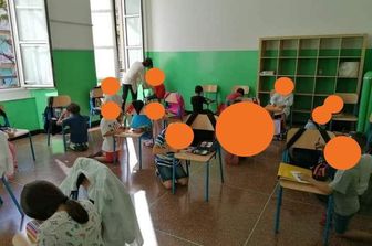 scuola Genova senza banchi bambini scrivono in ginocchio