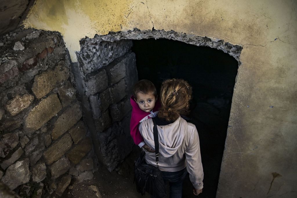 Una donna porta il bambino in un bunker a Shusha