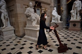 Un'addetta della Camera riporta in Aula il leggio di Nancy Pelosi