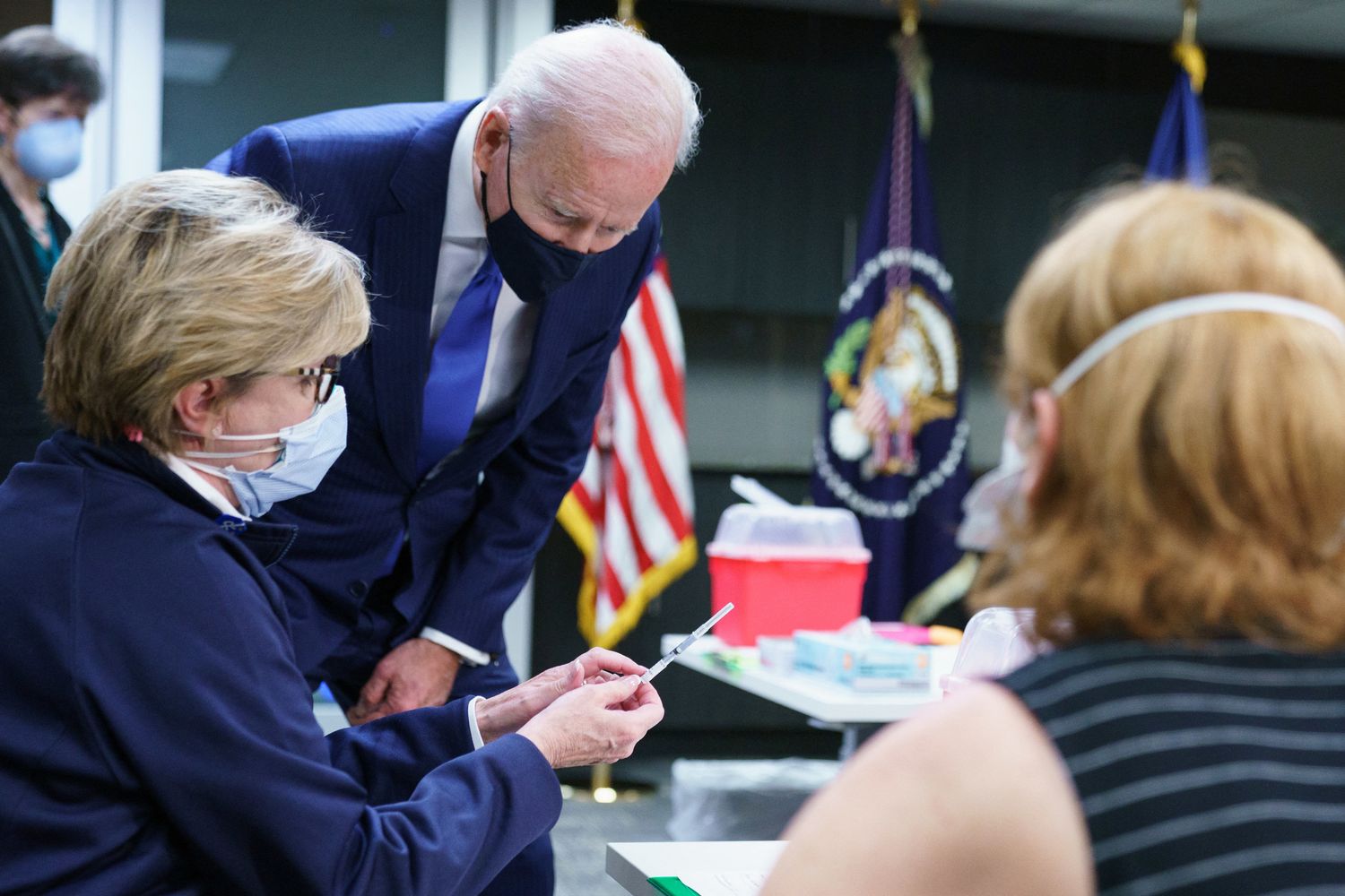 Joe Biden osserva una dose di vaccino prima che venga inoculato in un centro per veterani