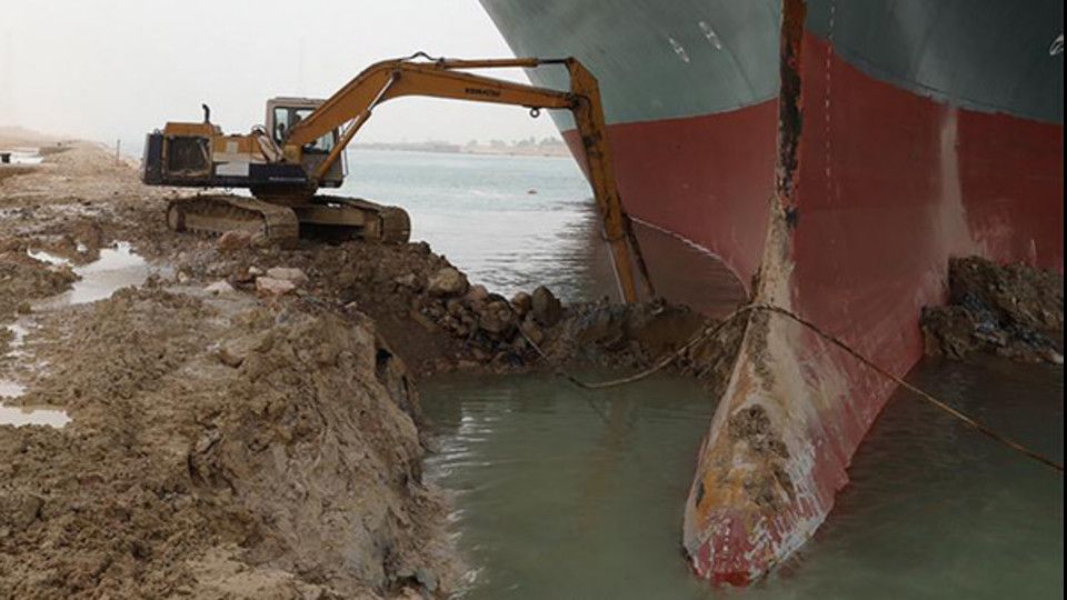 Un escavatore al lavoro per liberare la portacontainer incagliata nel Canale di Suez