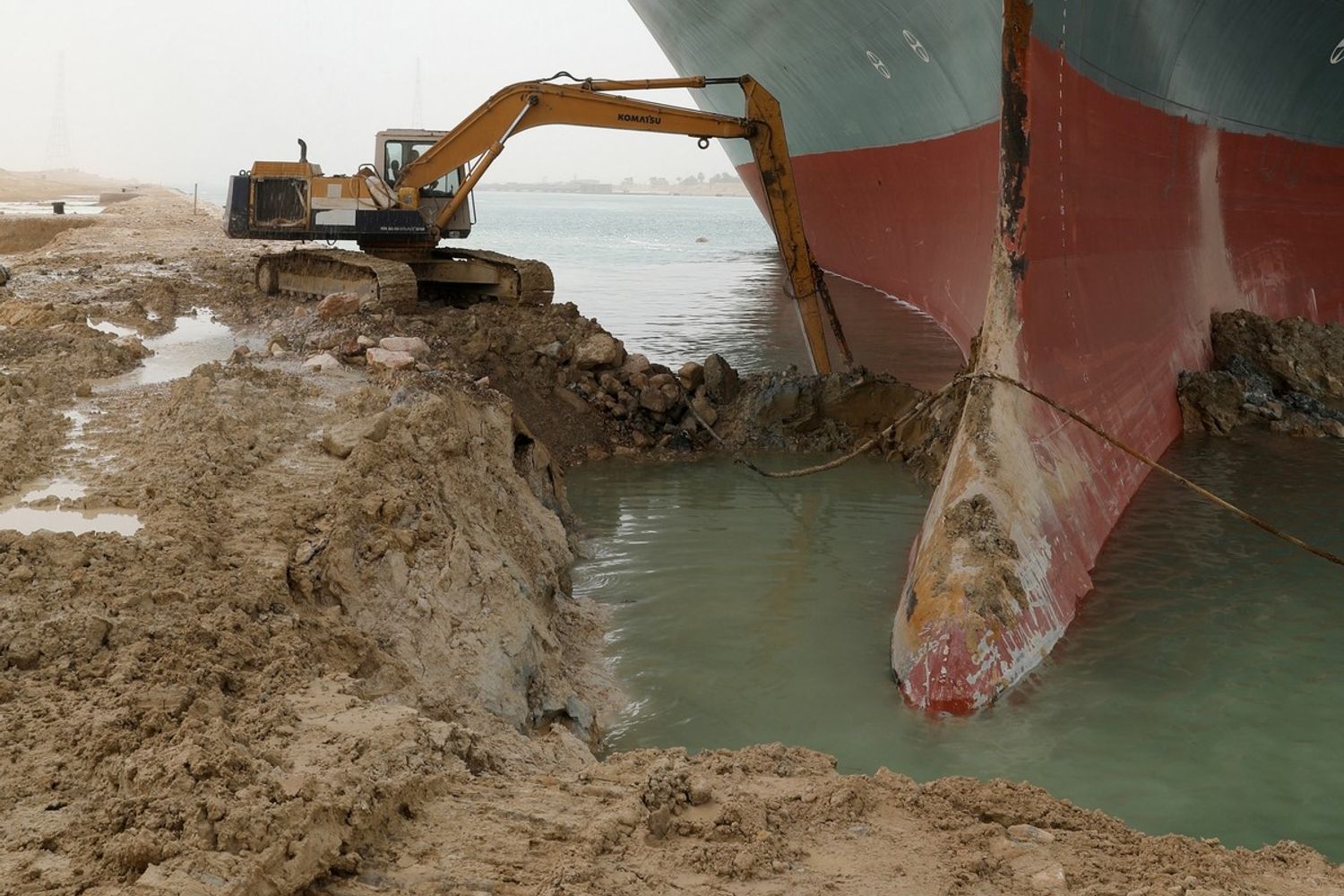 Una scavatrice prova a sbloccare la portacontainer che blocca il Canale di Suez