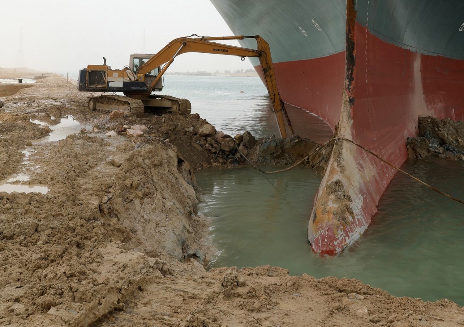 Una scavatrice prova a sbloccare la portacontainer che blocca il Canale di Suez