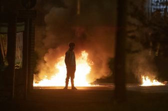 Un ragazzo guarda le fiamme causate dalla rivolta avvenuta nell'aprile 2021 a Newtownabbey, a nord di Belfast, in Irlanda del Nord