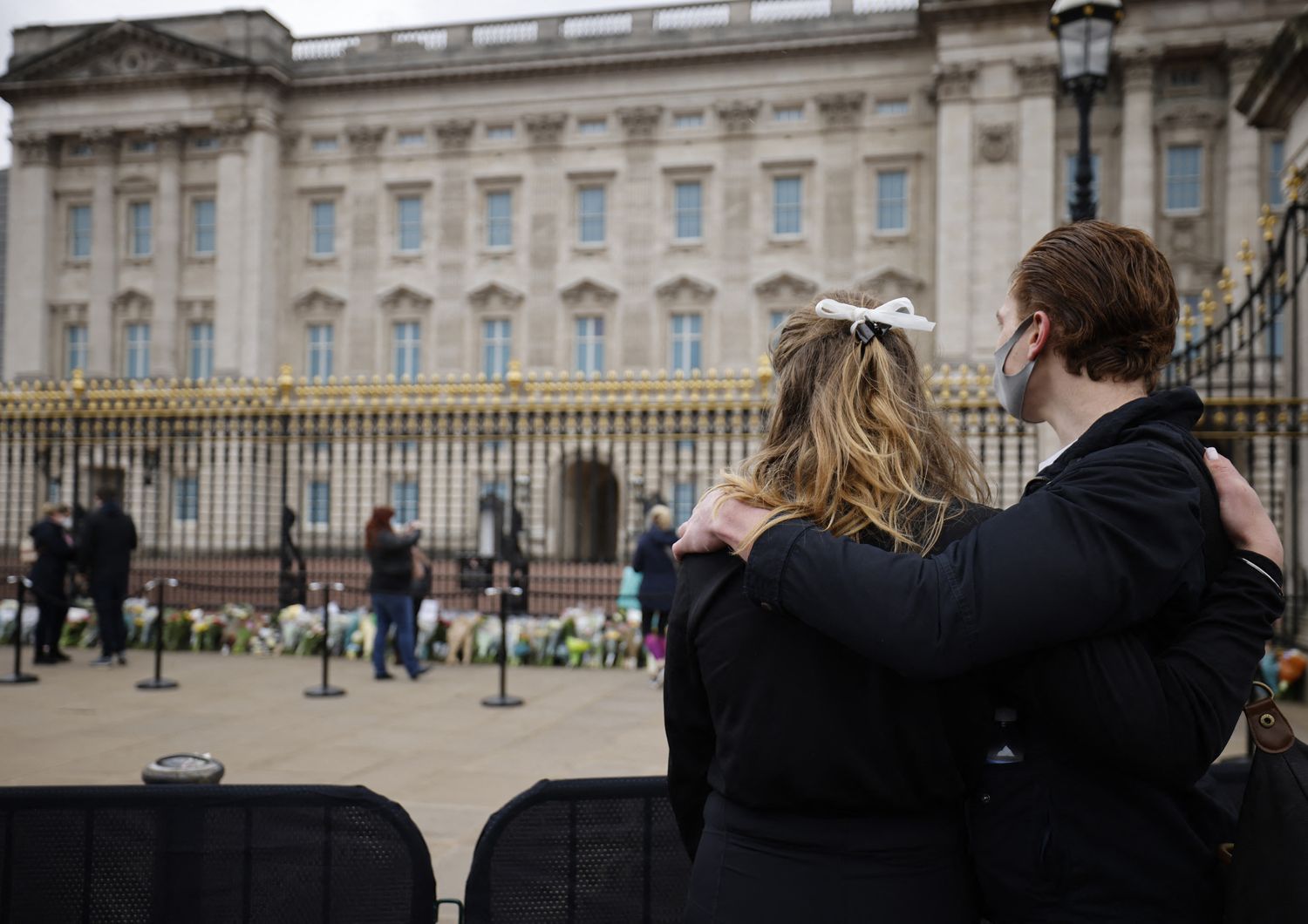 Una coppia davanti alle cancellate di Buckingham Palace dove sono stati lasciati omaggi floreali per la morte del principe Filippo