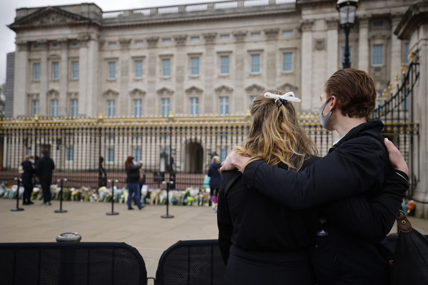 Una coppia davanti alle cancellate di Buckingham Palace dove sono stati lasciati omaggi floreali per la morte del principe Filippo