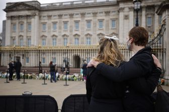 Una coppia davanti alle cancellate di Buckingham Palace dove sono stati lasciati omaggi floreali per la morte del principe Filippo