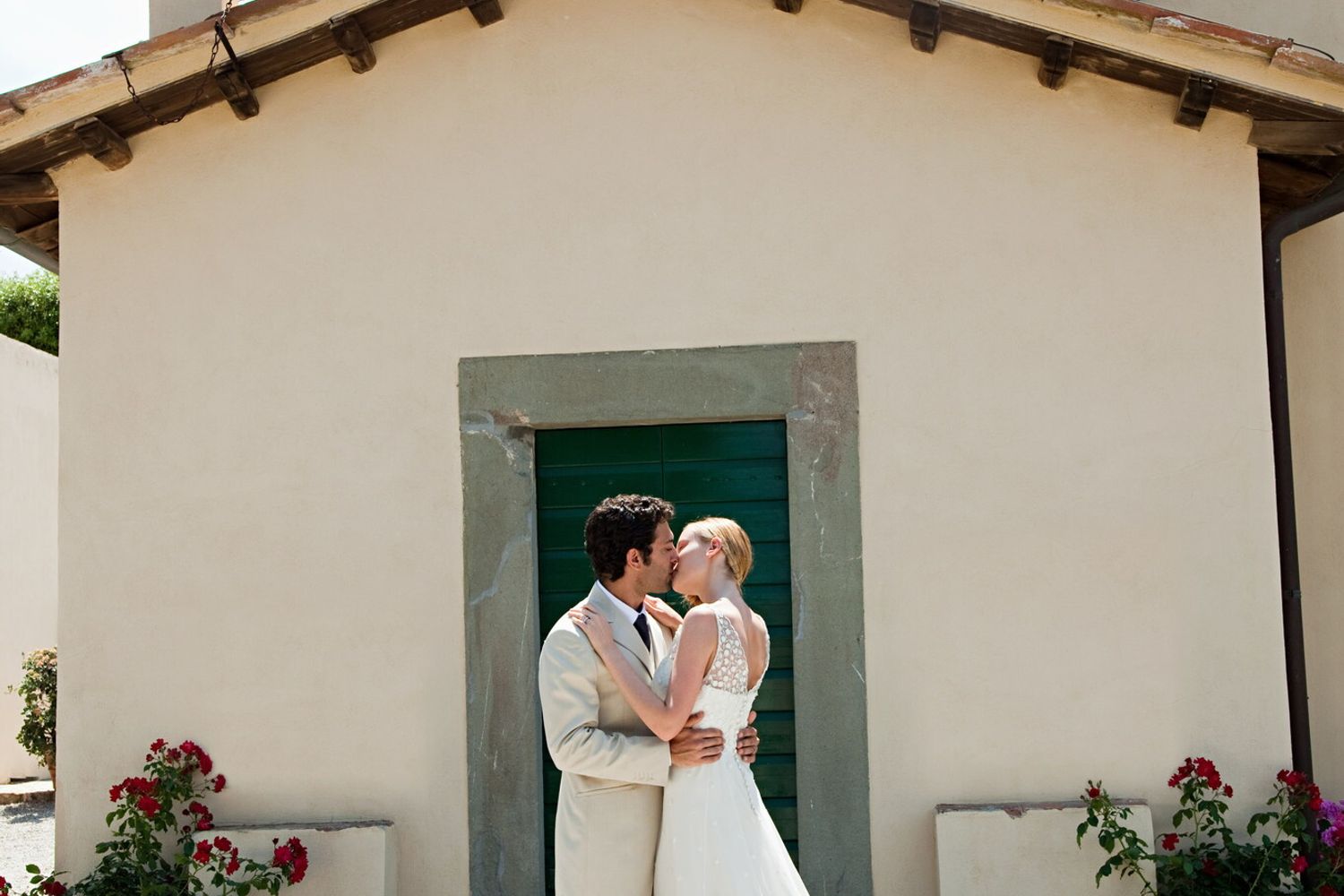 Il bacio di due sposini davanti alla chiesa dov'&egrave; stato celebrato il loro matrimonio