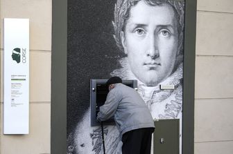 Un uomo preleva denaro da una bancomat decorato con il ritratto di Napoleone ad Ajaccio
