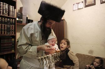 Israele: un ebreo ultraortodosso, con indosso il tradizionale copricapo di pelliccia, celebra Hannukah con la sua famiglia