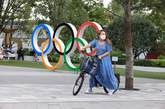 Tokyo: una donna davanti al simbolo delle Olimpiadi nel centro della capitale giapponese