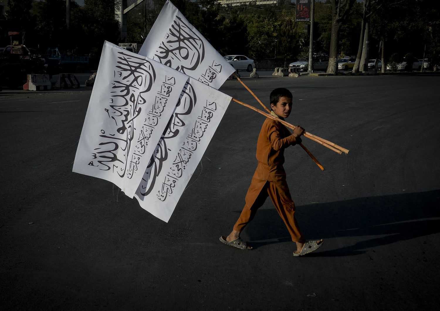 Un ragazzino porta bandiere dei talebani in una strada di Kabul