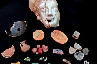 Il volto della dea Astarte/Afrodite con&nbsp;la decorazione pittorica bianca lucente sull&rsquo;incarnato, rossa nei riccioli che sbordano dal diadema dorato.