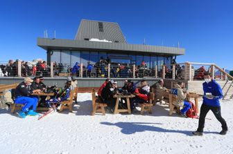 Uno ski bar ai piedi di una pista da sci inondata dal sole a Moena