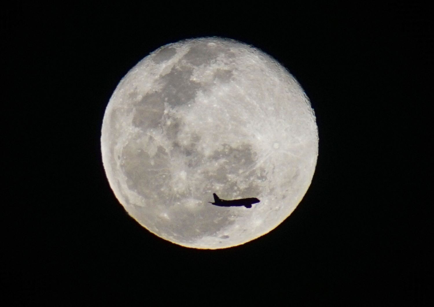 La sagoma di un aereo si staglia contro la Luna