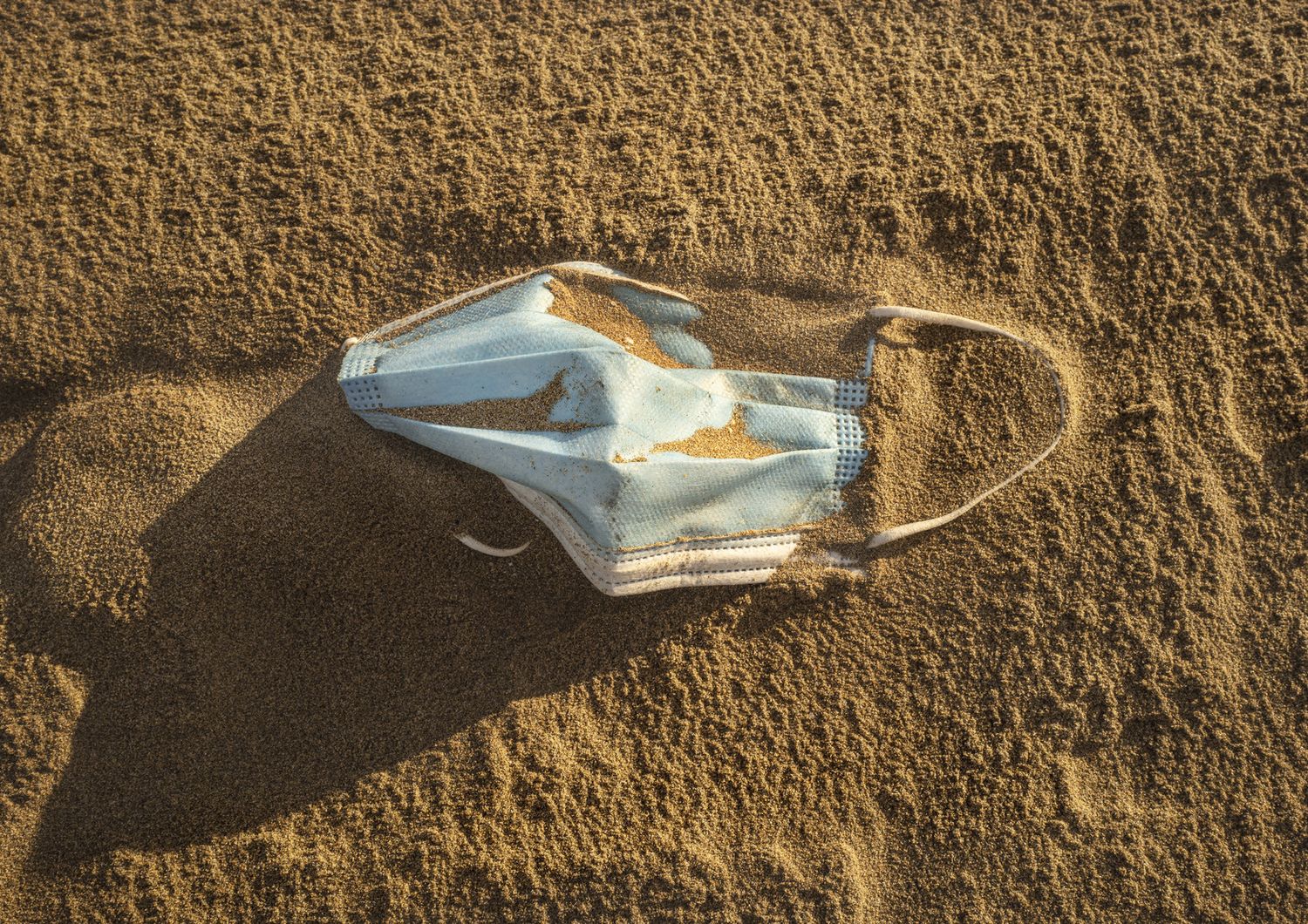 Una mascherina abbandonata in spiaggia