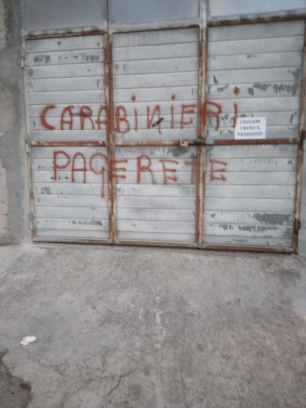 Una delle scritte contro i carabinieri comparsa su una serranda durante il raid vandalico a Ozieri (Sassari)