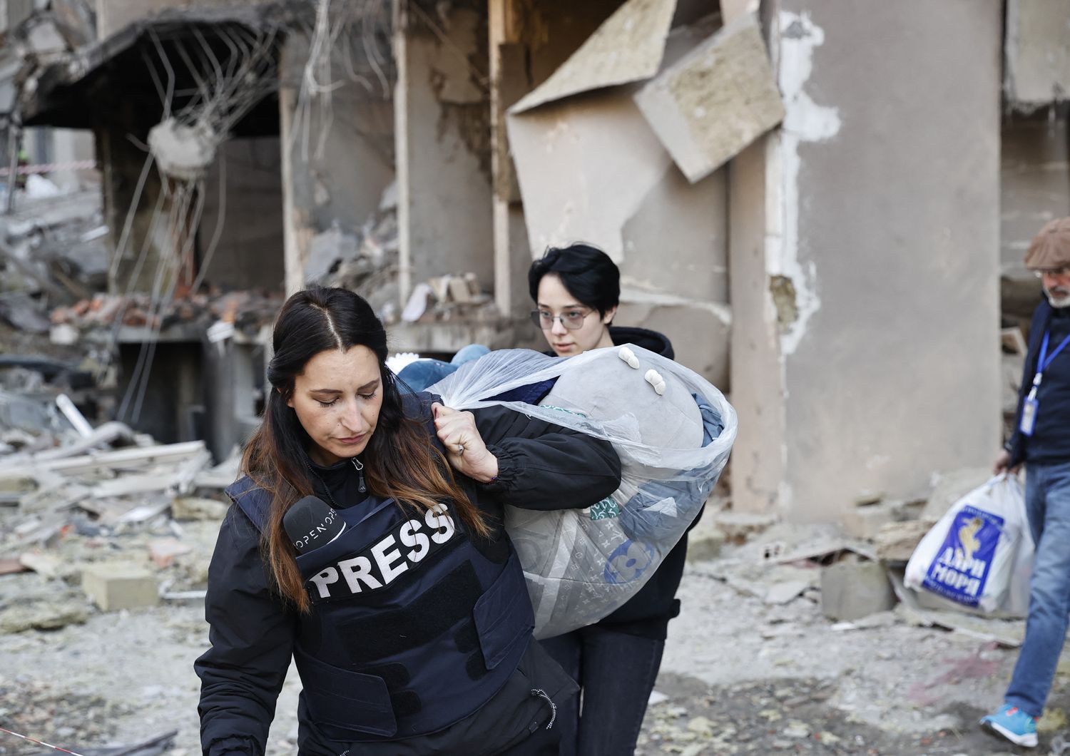 Un operatore dei media aiuta alcuni civili a sgomberare un edificio bombardato&nbsp;