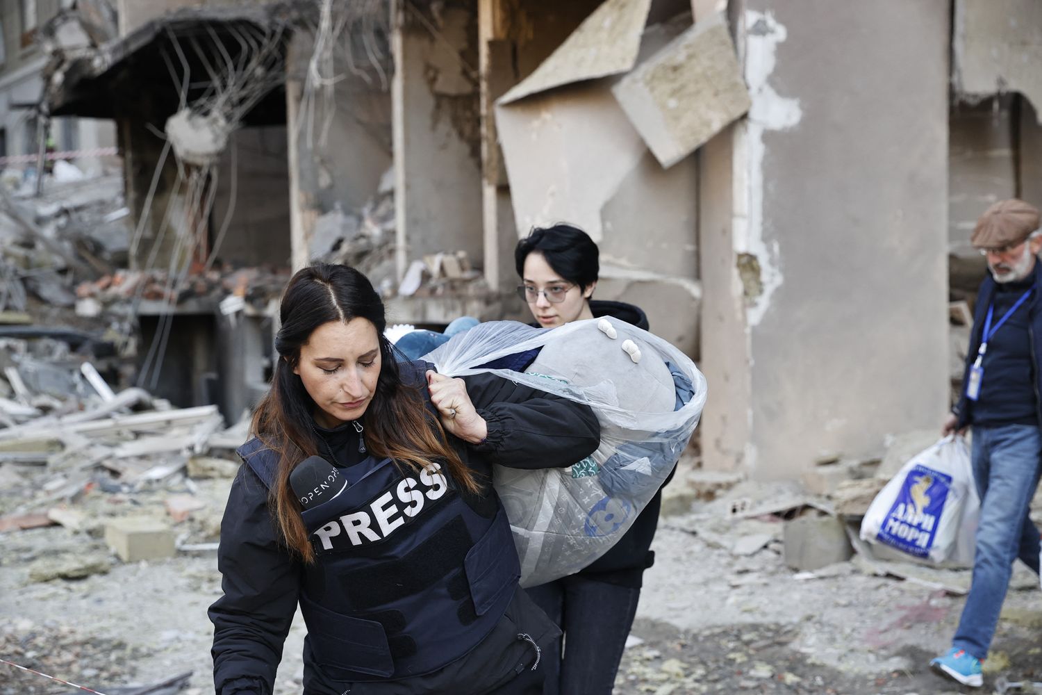 Un operatore dei media aiuta alcuni civili a sgomberare un edificio bombardato&nbsp;