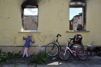 Una bambina ucraina disegna sul muro di un edificio distrutto dalle bombe&nbsp;