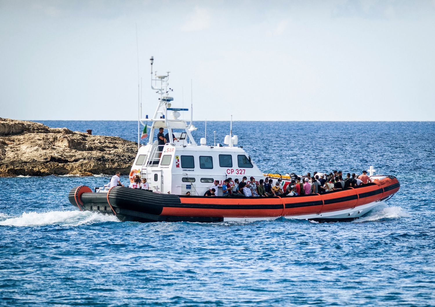 Migranti arrivano a Lampedusa su un'imbarcazione della Guardia di Finanza