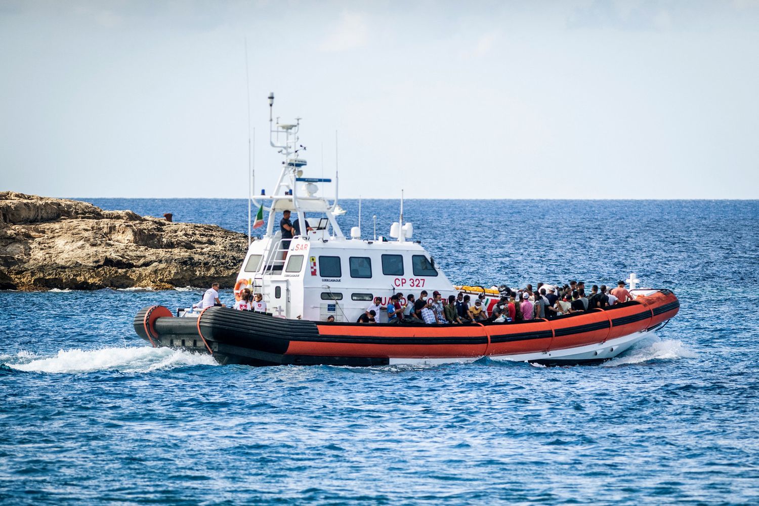 Migranti arrivano a Lampedusa su un'imbarcazione della Guardia di Finanza