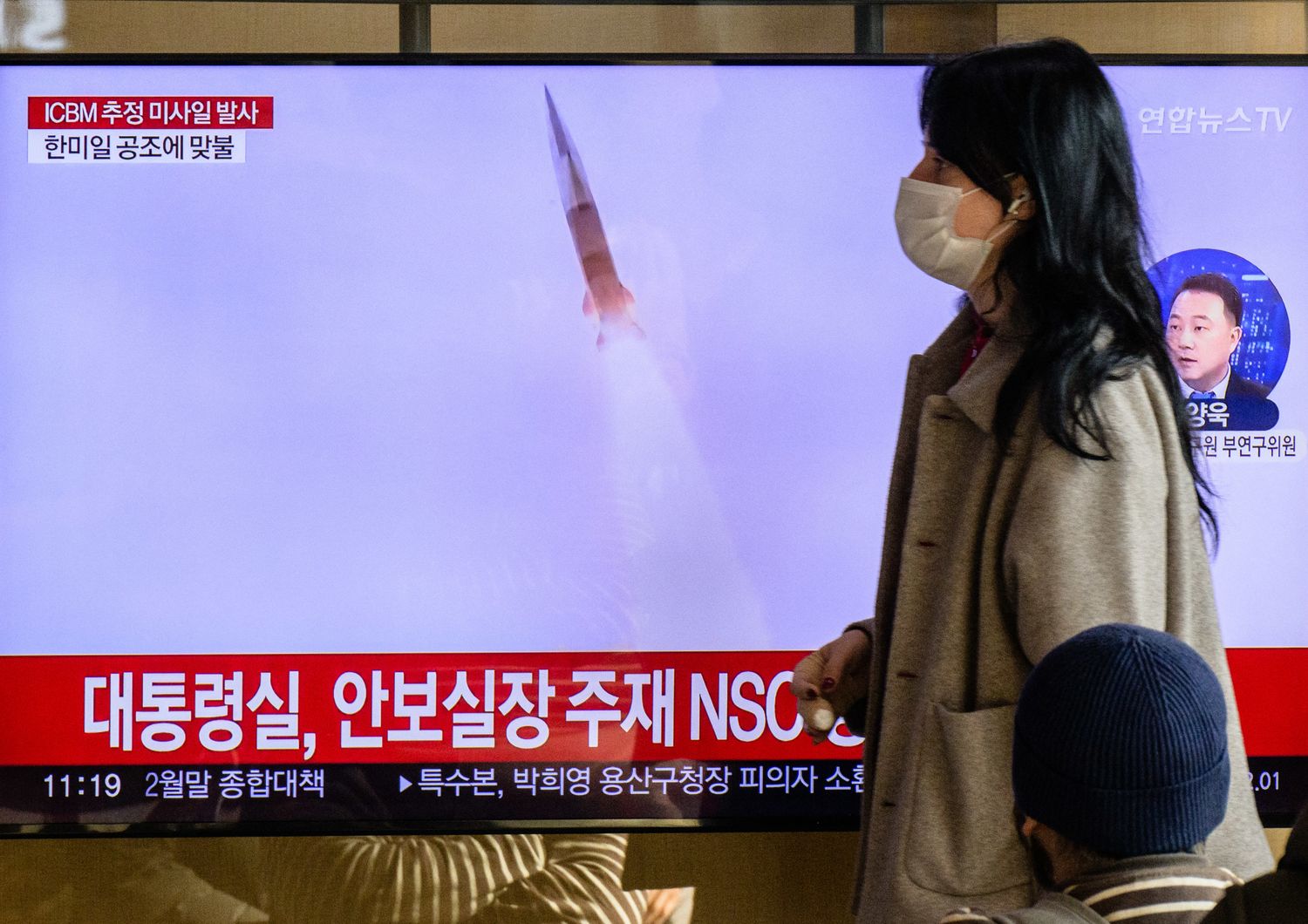 Una donna passa davanti a uno schermo che trasmette la notizia del lancio di un missile nordcoreano