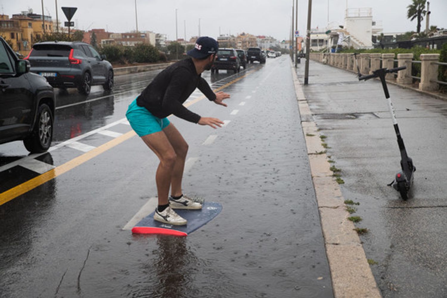 Un ragazzo in surf lungo la pista ciclabile allagata di Ostia a Roma &nbsp;