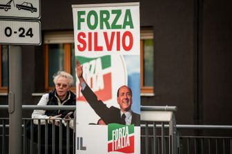Una simpatizzante del leader di Forza Italia dietro al totem di Berlusconi all'ingresso del San Raffaele di Milano &nbsp;