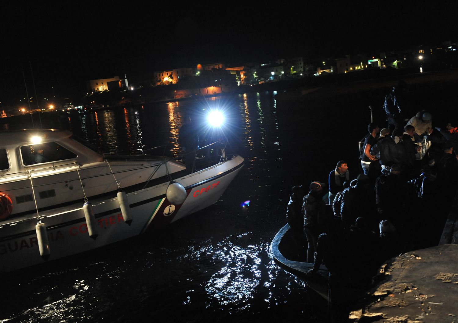 Lampedusa, porto, nella foto alcuni sbarchi al molo di notte, motovedetta della guardia costiera