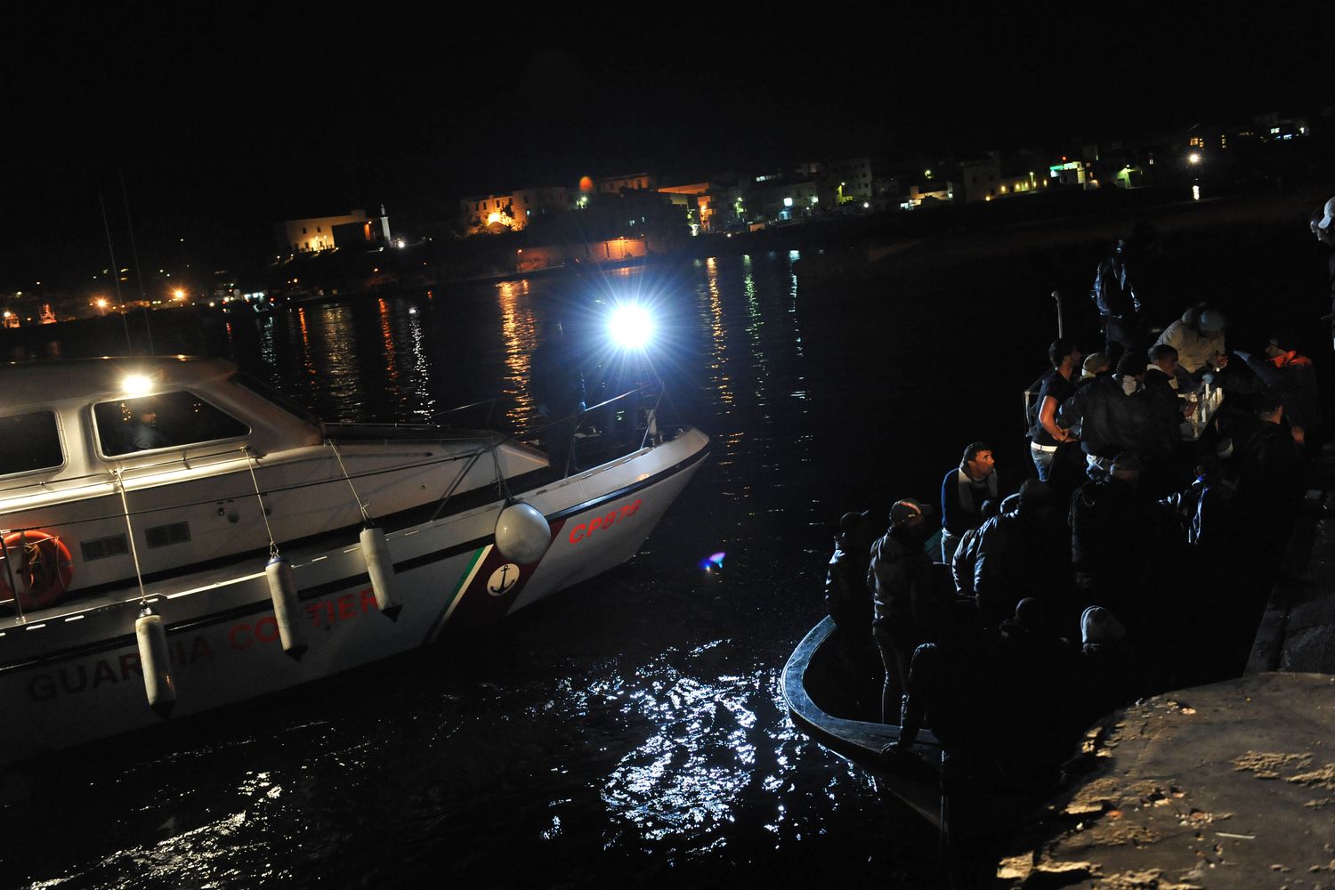 Lampedusa, porto, nella foto alcuni sbarchi al molo di notte, motovedetta della guardia costiera