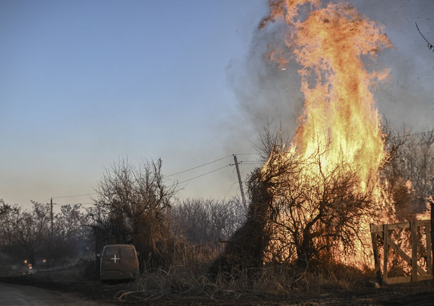 Alberi bruciano accanto a un veicolo militare ucraino, dopo l'esplosione di munizioni al fosforo bianco a Chasiv Yar, vicino a Bakhmut, il 14 marzo 2023.&nbsp;