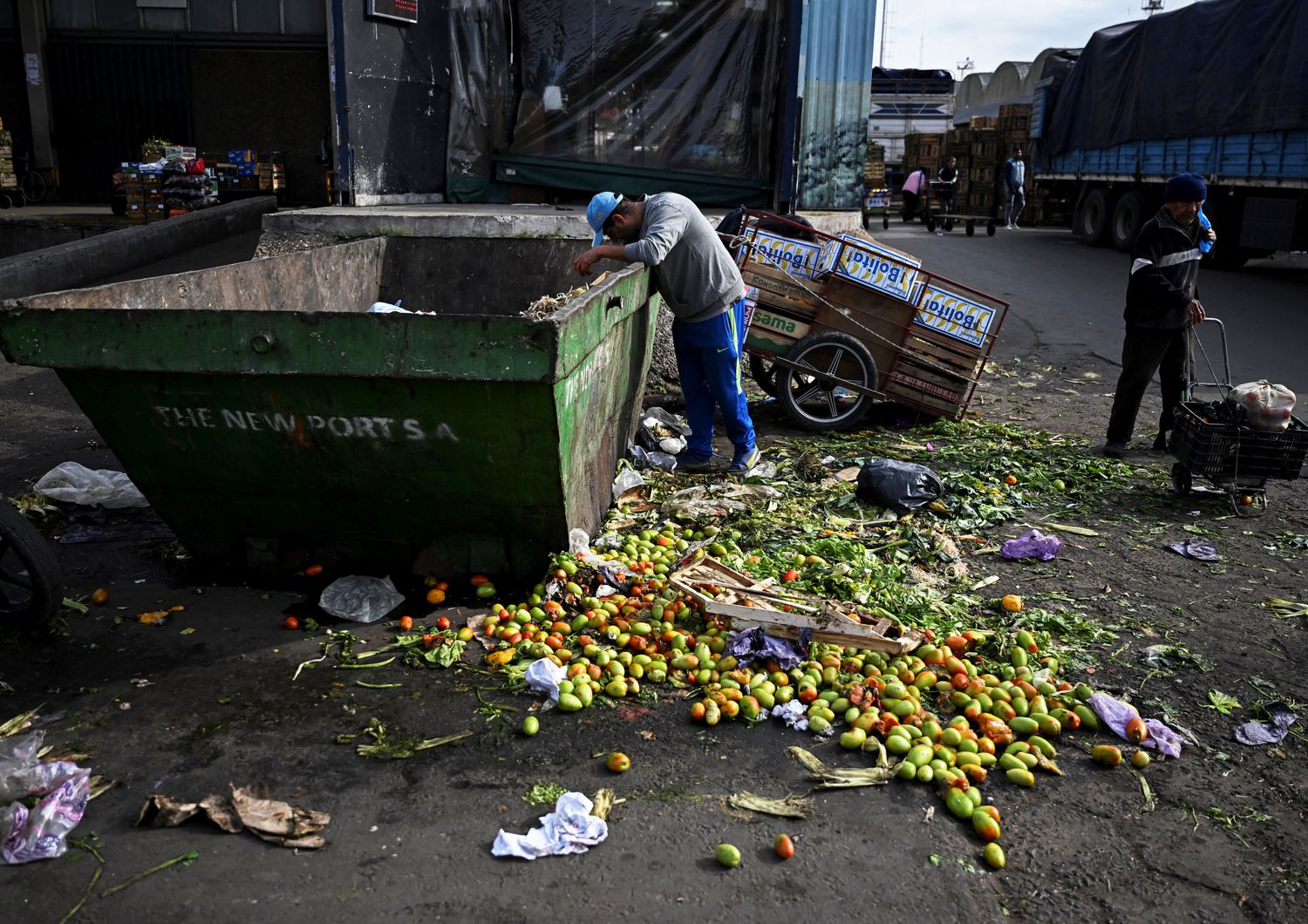 Povert&agrave; in Argentina - un uomo rovista tra la verdura scartata al mercato di Buenos Aires