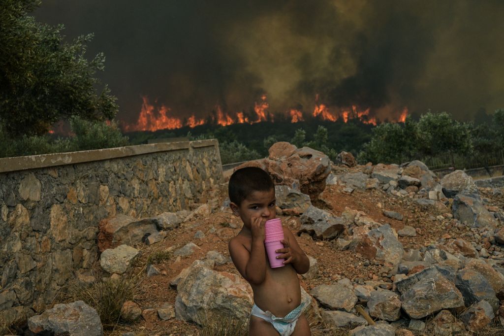 Un bambino nel villaggio in fiamme di Agios Charalabos, a 70 Km da Atene