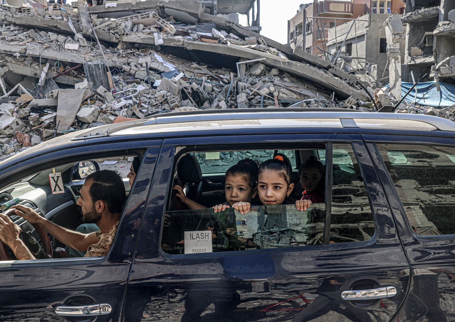 Palestinesi in fuga tra le macerie di edifici distrutti da un attacco aereo israeliano a Rafah, nel sud della Striscia di Gaza&nbsp;