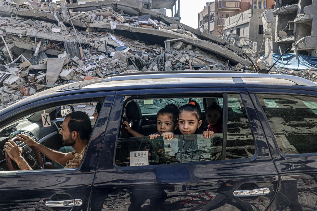 Palestinesi in fuga tra le macerie di edifici distrutti da un attacco aereo israeliano a Rafah, nel sud della Striscia di Gaza&nbsp;