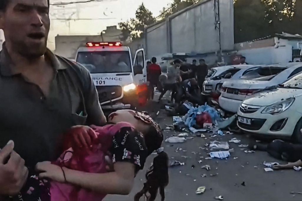 Un uomo porta una bambina ferita in braccio a Gaza dopo un raid israeliano