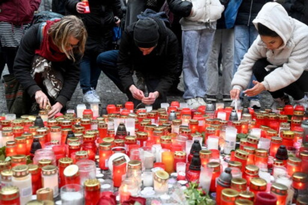 Dei ragazzi accendono le candele in un memoriale improvvisato per le vittime fuori dall'Universit&agrave; Carlo