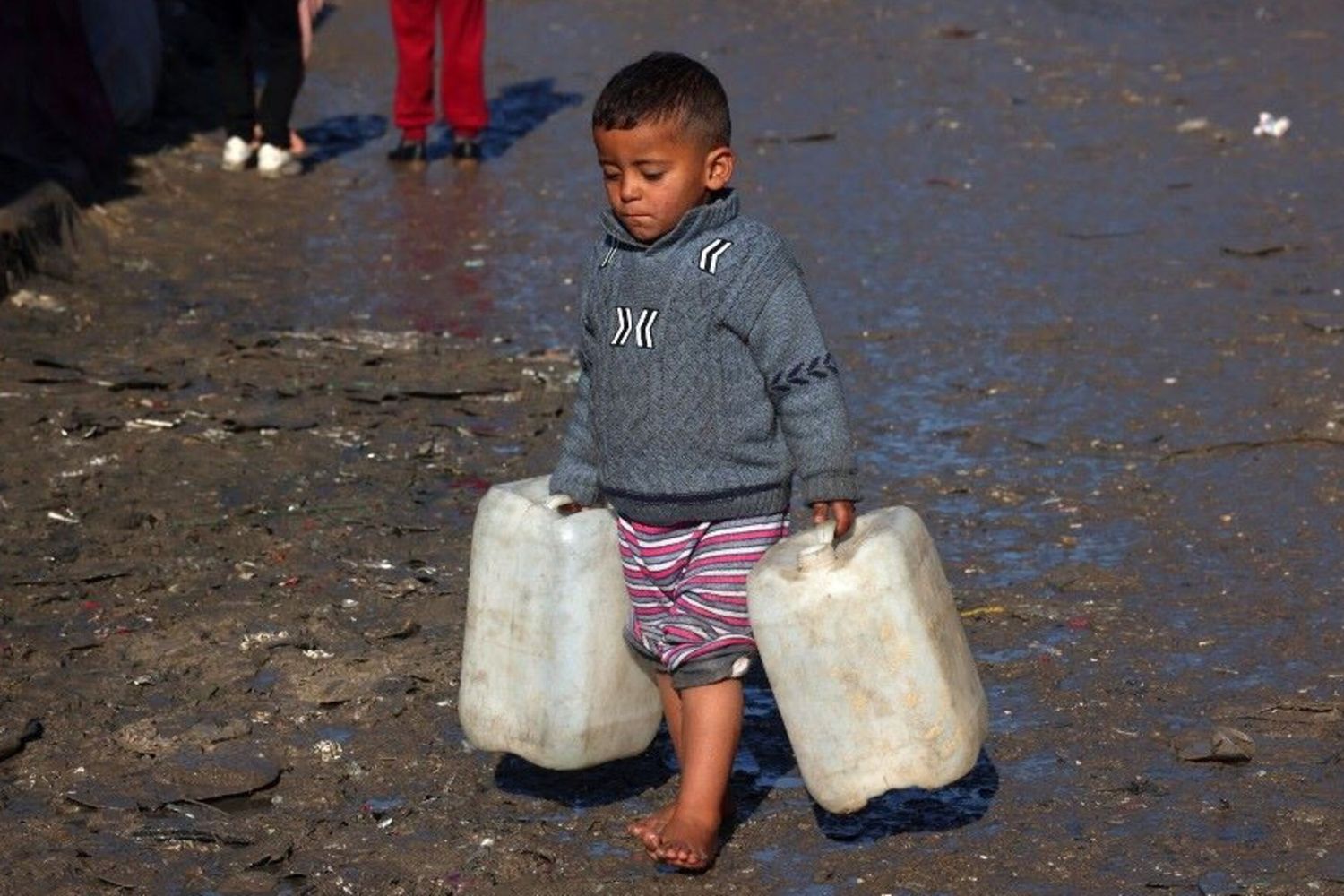 Un bambino trasporta delle taniche vuote a Rafah, nel sud della Striscia di Gaza, mentre continuano i combattimenti tra Israele e il gruppo palestinese di Hamas