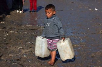 Un bambino trasporta delle taniche vuote a Rafah, nel sud della Striscia di Gaza, mentre continuano i combattimenti tra Israele e il gruppo palestinese di Hamas