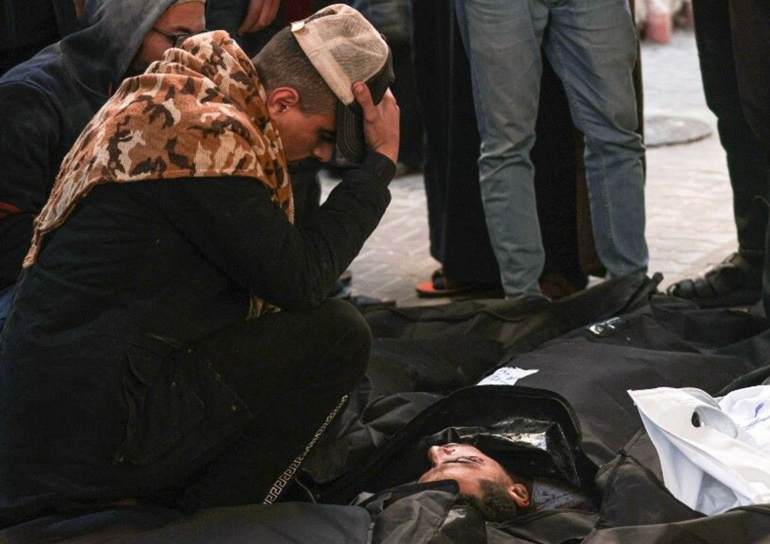 Un uomo si inginocchia davanti al corpo di un parente ucciso da un bombardamento israeliano, all'ospedale Najjar di Rafah, il 3 febbraio 2024