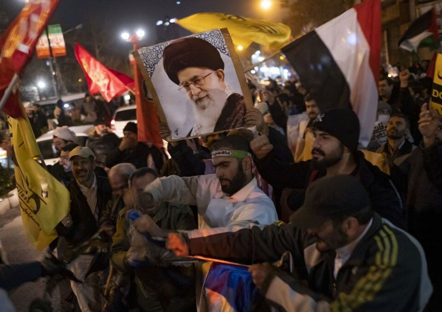 Iraniani, durante una protesta anti Usa-Gb, portano un ritratto della Guida Suprema iraniana, l'Ayatollah Ali Khamenei, e una bandiera yemenita mentre strappano una bandiera israeliana
