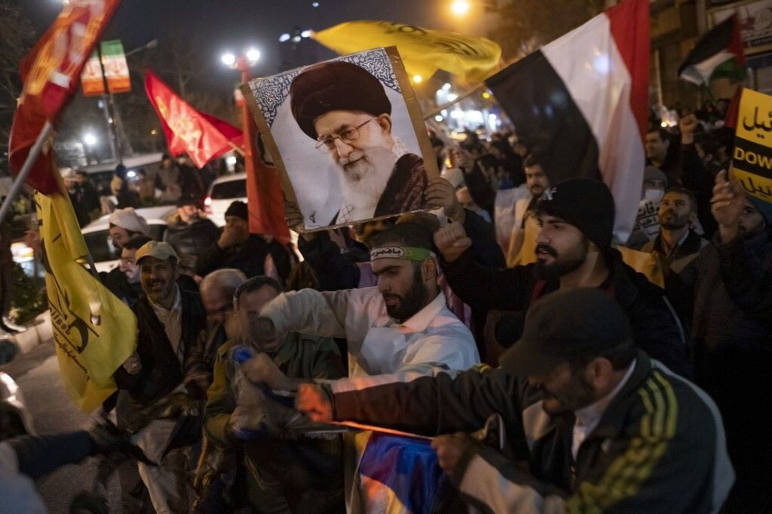 Iraniani, durante una protesta anti Usa-Gb, portano un ritratto della Guida Suprema iraniana, l'Ayatollah Ali Khamenei, e una bandiera yemenita mentre strappano una bandiera israeliana