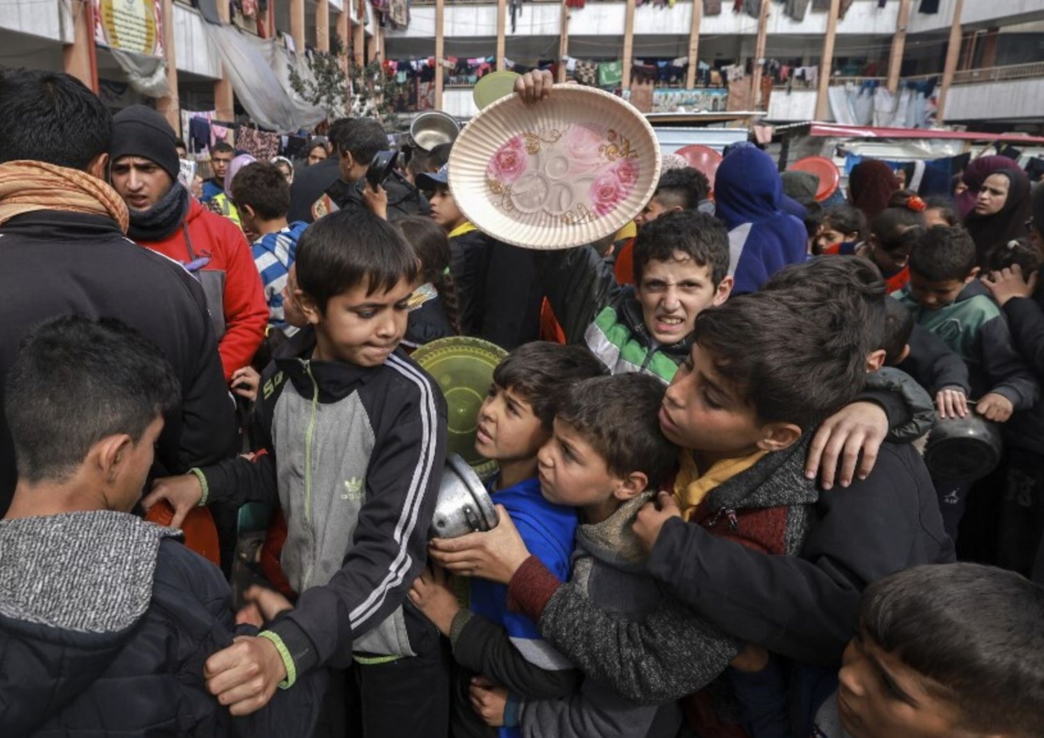 Bambini palestinesi sfollati si riuniscono per ricevere cibo in una scuola governativa a Rafah