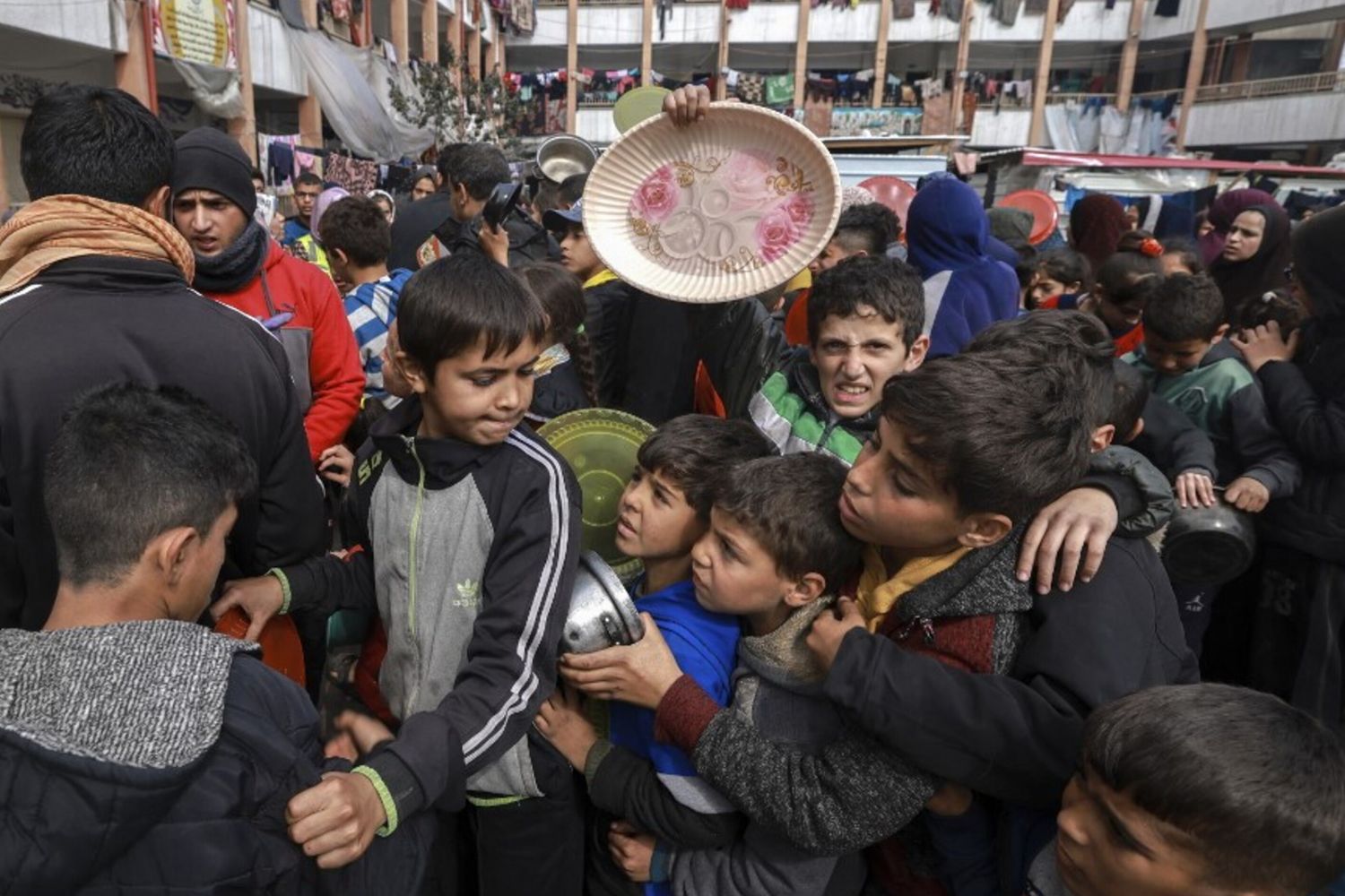 Bambini palestinesi sfollati si riuniscono per ricevere cibo in una scuola governativa a Rafah