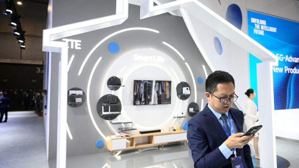 Un uomo usa il suo telefono sullo stand dell'azienda cinese ZTE durante il Mobile World Congress (MWC)