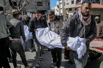 Palestinesi trasportano il corpo di un uomo morto nell'assalto ai camion di aiuti
