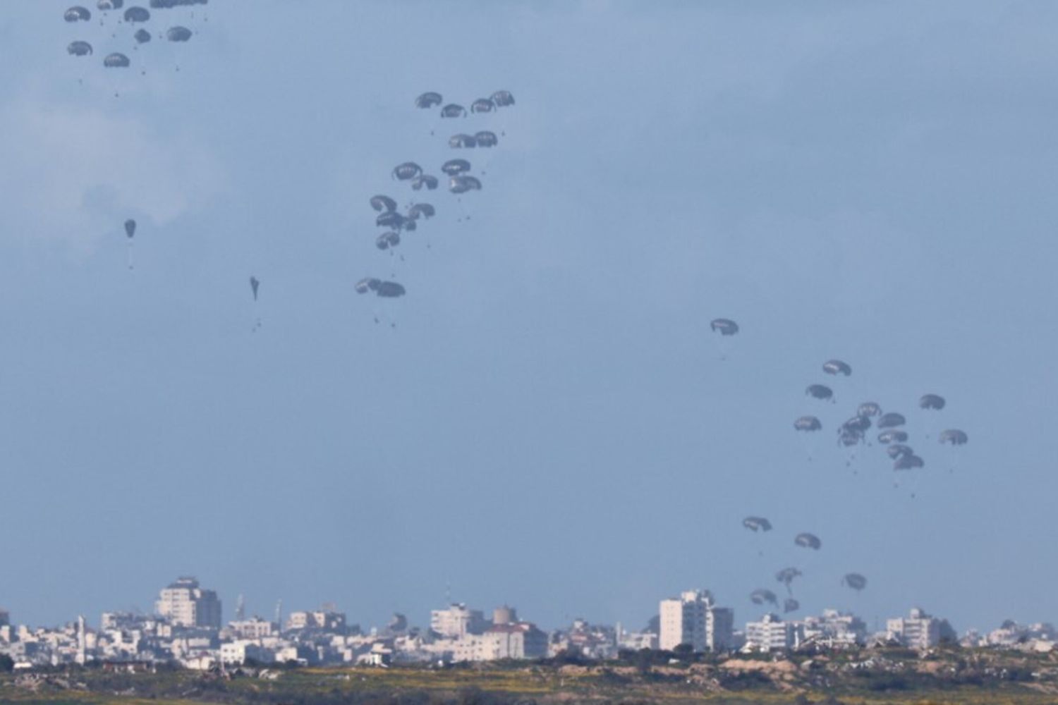 Aiuti umanitari cadono sul nord di Gaza, visti dal confine meridionale di Israele con la Striscia, il 7 marzo 2024, durante il conflitto in corso tra Israele e Hamas